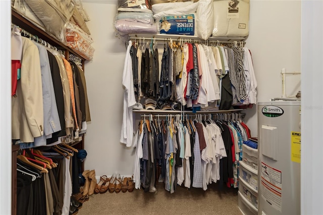 walk in closet featuring electric water heater and dark carpet