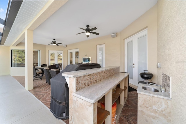 view of terrace featuring a bar, french doors, ceiling fan, and exterior kitchen