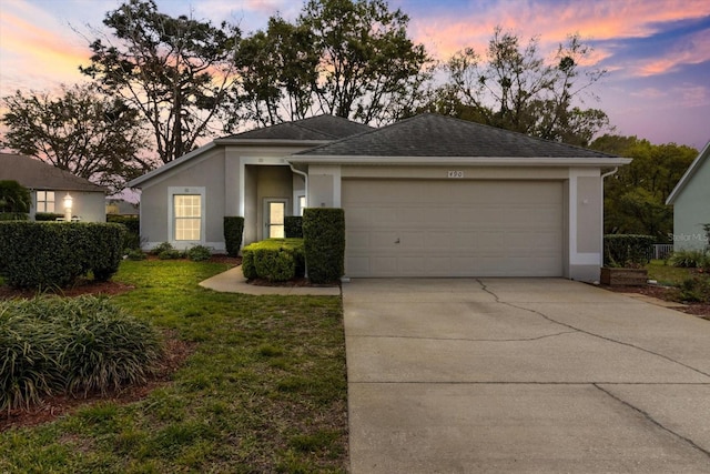 view of front of property with roof with shingles, stucco siding, concrete driveway, a lawn, and a garage