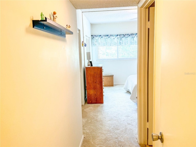 corridor with a textured ceiling and light colored carpet