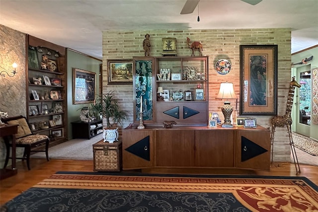 interior space with brick wall, ceiling fan, and dark hardwood / wood-style floors