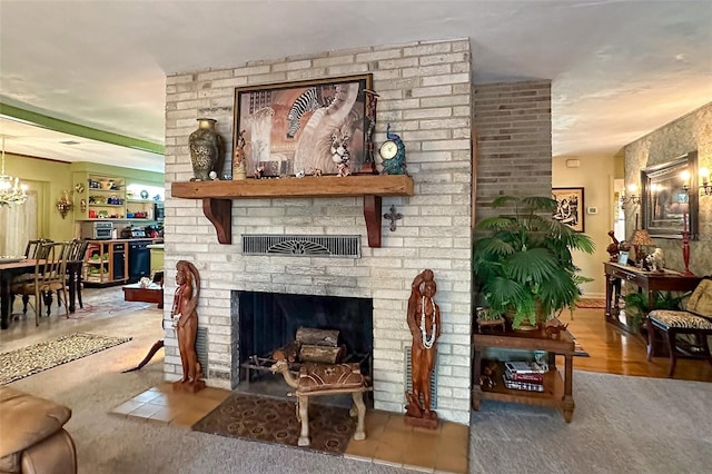 living room featuring a chandelier, a brick fireplace, brick wall, and light wood-type flooring