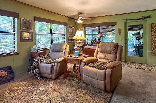 interior space featuring dark colored carpet, ornamental molding, ceiling fan, and a wealth of natural light