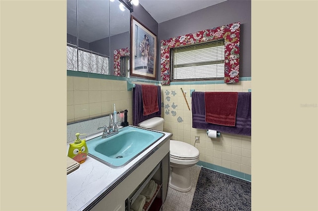 bathroom featuring tile walls, tile flooring, toilet, and vanity