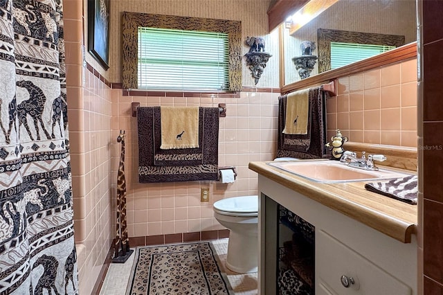 bathroom with tile walls, large vanity, toilet, and tile flooring