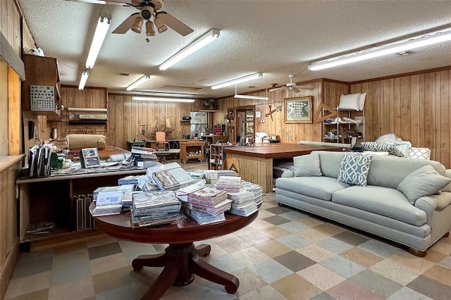 interior space featuring wooden walls, a textured ceiling, and ceiling fan