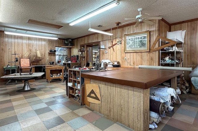 interior space with wood walls, ceiling fan, and a textured ceiling