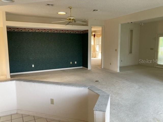 spare room featuring a textured ceiling, light colored carpet, ceiling fan, and a wealth of natural light