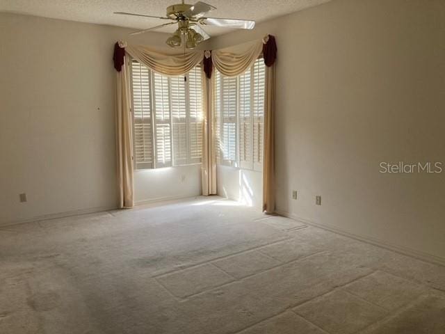 empty room with plenty of natural light, a textured ceiling, ceiling fan, and light colored carpet