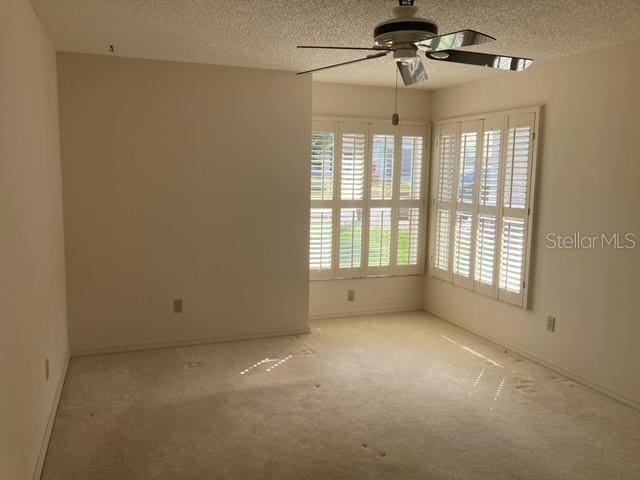 unfurnished room with light colored carpet, ceiling fan, and a textured ceiling