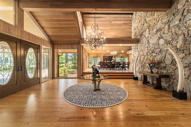 foyer entrance featuring beam ceiling, a notable chandelier, light wood-type flooring, and french doors