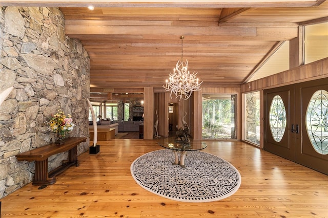 foyer entrance featuring french doors, light hardwood / wood-style floors, wooden ceiling, a notable chandelier, and vaulted ceiling with beams