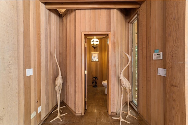 hallway with wooden walls and dark tile floors