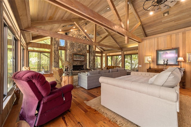 living room featuring wood ceiling, dark hardwood / wood-style flooring, a stone fireplace, and beamed ceiling