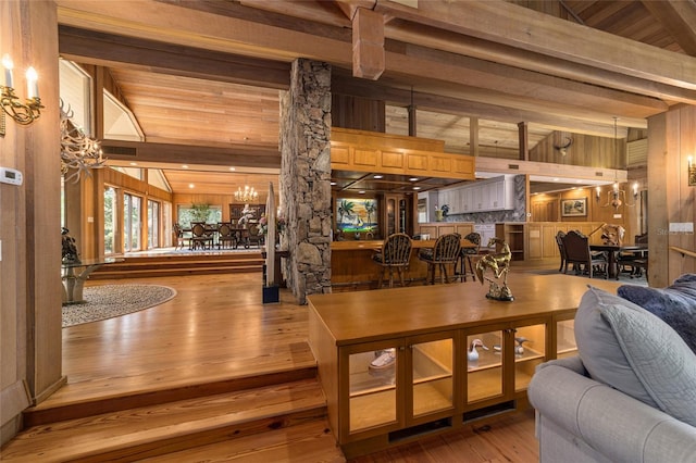 interior space featuring vaulted ceiling with beams, wood walls, a notable chandelier, and hardwood / wood-style flooring