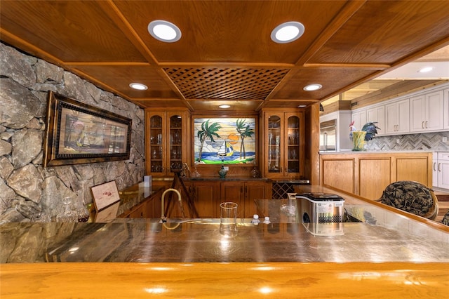 bar with white cabinets, backsplash, and stainless steel counters