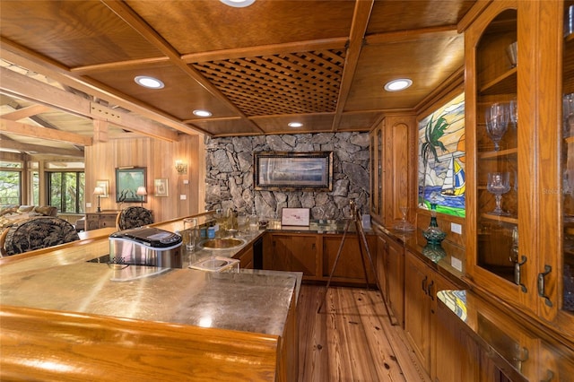 interior space with dark hardwood / wood-style floors, wooden walls, sink, stainless steel counters, and a stone fireplace