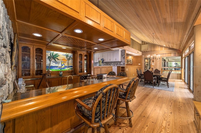 bar featuring light hardwood / wood-style floors, wooden ceiling, pendant lighting, and lofted ceiling