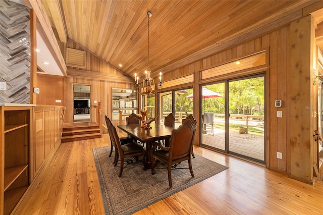 dining room featuring a chandelier, wooden walls, wooden ceiling, and light wood-type flooring