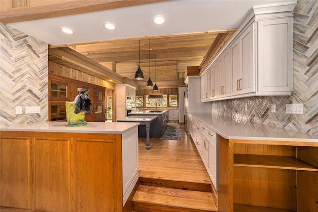 kitchen featuring hanging light fixtures, white cabinetry, sink, a center island, and hardwood / wood-style flooring