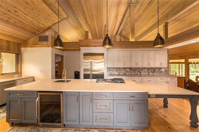 kitchen featuring decorative light fixtures, wine cooler, stainless steel appliances, and light wood-type flooring