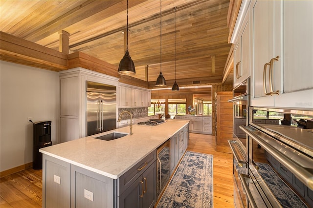 kitchen with gray cabinetry, a kitchen island with sink, stainless steel appliances, wooden ceiling, and pendant lighting