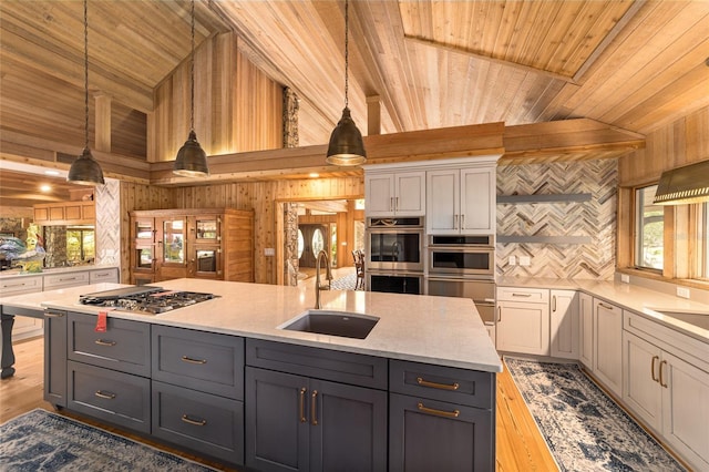 kitchen featuring gray cabinetry, decorative light fixtures, sink, an island with sink, and wooden ceiling