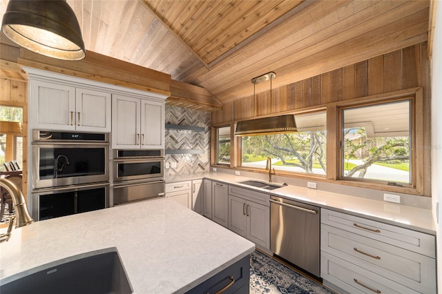 kitchen featuring tasteful backsplash, stainless steel appliances, wood ceiling, and sink