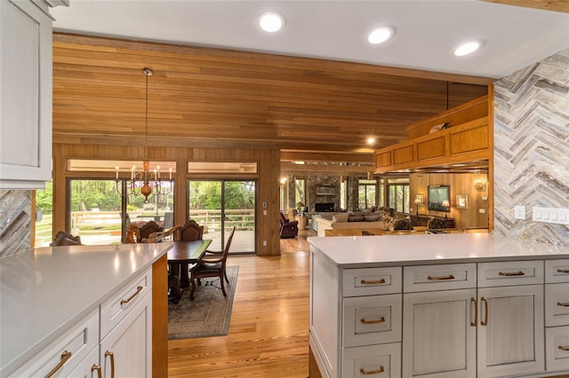 kitchen with pendant lighting, a notable chandelier, light wood-type flooring, and a wealth of natural light