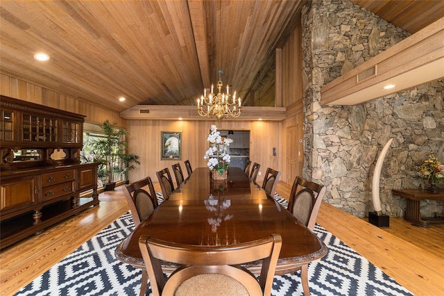 dining space with an inviting chandelier, wooden ceiling, wooden walls, and light hardwood / wood-style flooring