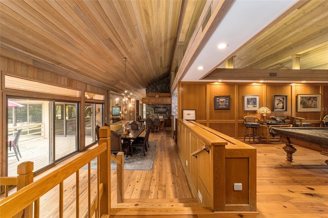 interior space with wood walls, wood ceiling, vaulted ceiling, and light wood-type flooring