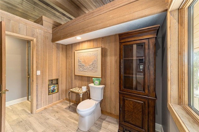 bathroom featuring hardwood / wood-style flooring, wooden walls, and toilet