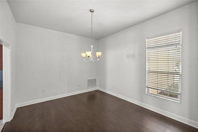 empty room featuring dark hardwood / wood-style floors and an inviting chandelier