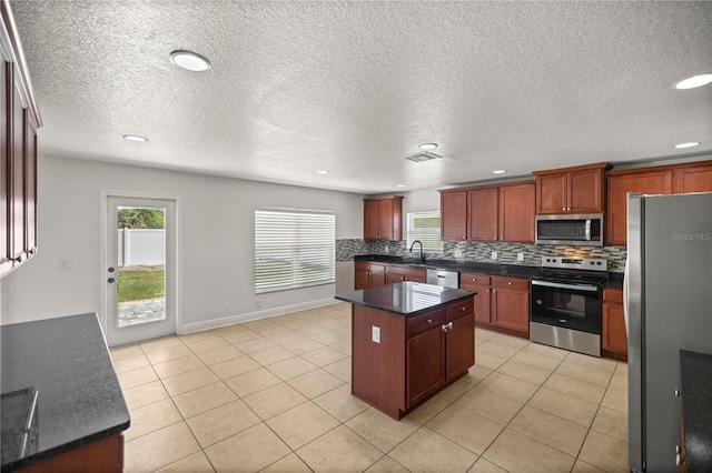 kitchen featuring light tile floors, a kitchen island, backsplash, and stainless steel appliances