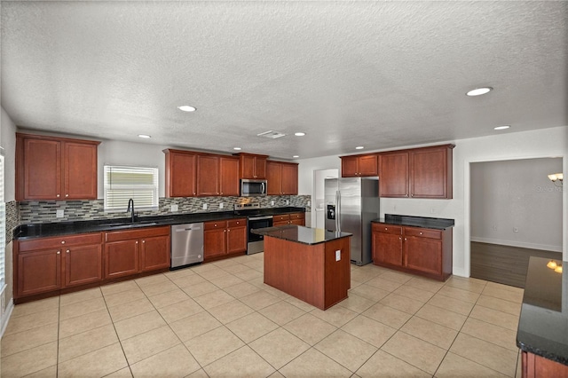 kitchen featuring light tile flooring, sink, appliances with stainless steel finishes, and a center island