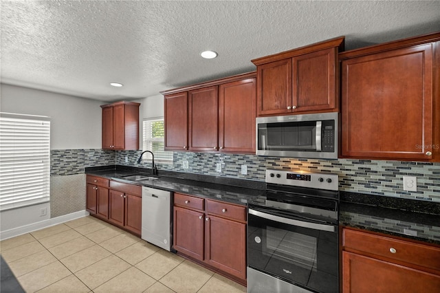 kitchen with dark stone counters, tasteful backsplash, stainless steel appliances, and sink