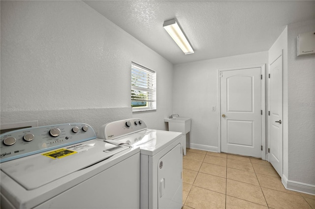 laundry area with light tile flooring, independent washer and dryer, and a textured ceiling