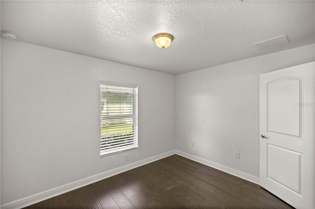 spare room featuring dark hardwood / wood-style floors and a textured ceiling