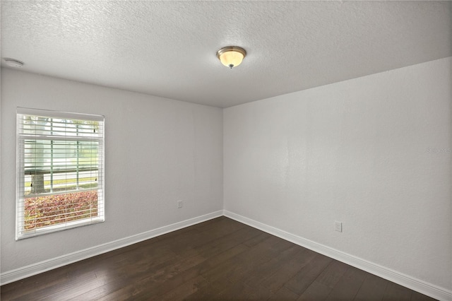 spare room featuring dark hardwood / wood-style floors, a textured ceiling, and a wealth of natural light