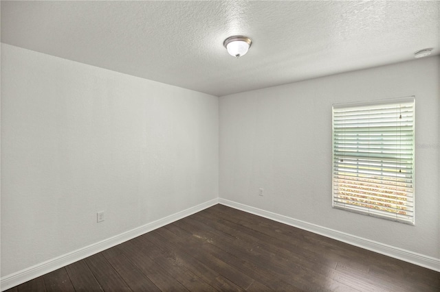 spare room featuring plenty of natural light, a textured ceiling, and dark hardwood / wood-style floors