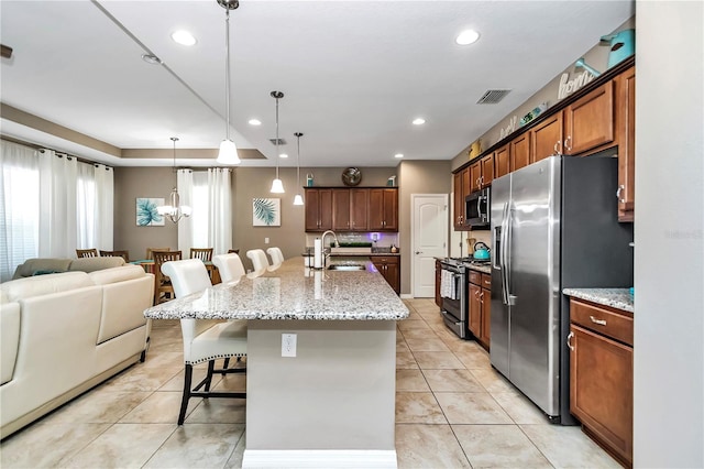 kitchen featuring pendant lighting, stainless steel appliances, an inviting chandelier, light stone counters, and sink