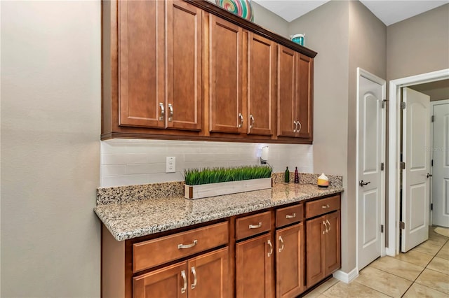 kitchen featuring light tile floors, light stone countertops, and backsplash