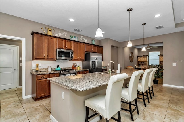 kitchen with hanging light fixtures, ceiling fan, a breakfast bar area, and stainless steel appliances