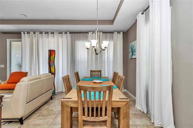 tiled dining room with plenty of natural light, a chandelier, and a raised ceiling