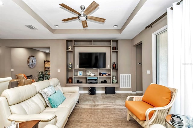 tiled living room featuring ceiling fan and a raised ceiling