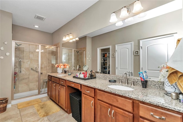 bathroom with a shower with door, tile flooring, and double sink vanity