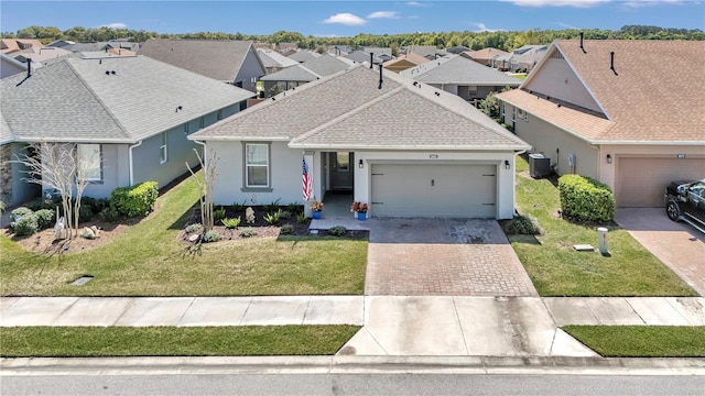 view of front facade featuring a front yard, a garage, and central air condition unit