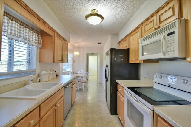 kitchen with light tile floors, a textured ceiling, white appliances, hanging light fixtures, and sink