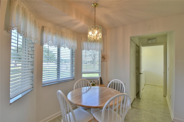 dining area with light tile floors, a textured ceiling, and a chandelier