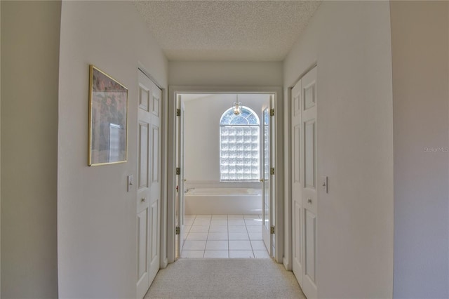 hall featuring a textured ceiling and light colored carpet